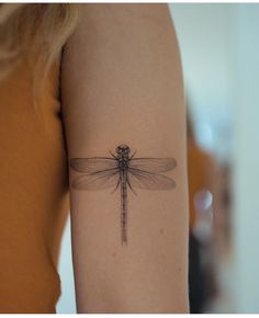 a woman's arm with a tattoo of a dragonfly on the back of her arm