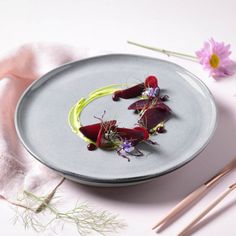 a plate with some food on it next to chopsticks and flowers in the background