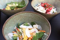 three bowls filled with different types of food on top of a black tableclothed surface