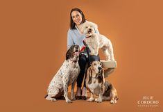 a woman sitting on top of a chair with three dogs in front of her smiling