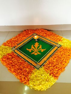 an arrangement of yellow and orange flowers with a candle in the center on a white floor