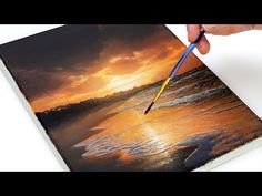 someone is painting a sunset on the beach with water and clouds in the background, using a brush