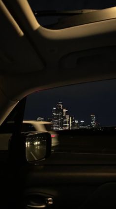 the view from inside a car at night with city lights in the background