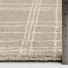 a measuring tape is on top of a beige area rug that has squares and lines