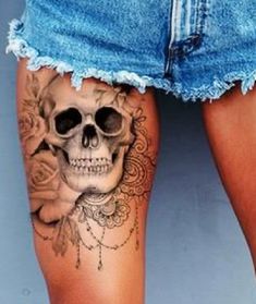 a woman's thigh with a skull and roses tattoo on it, next to her legs