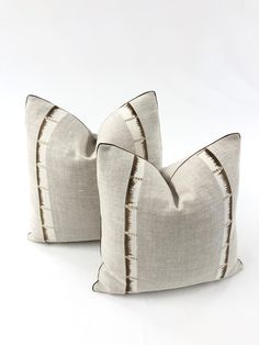 two gray and white striped pillows sitting on top of each other in front of a white background