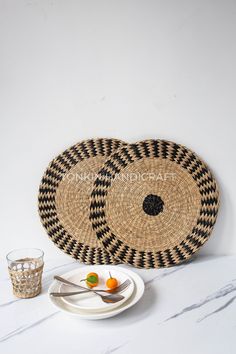 two black and white baskets sitting on top of a table next to a plate with an orange