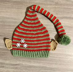 a red and green knitted hat sitting on top of a wooden table