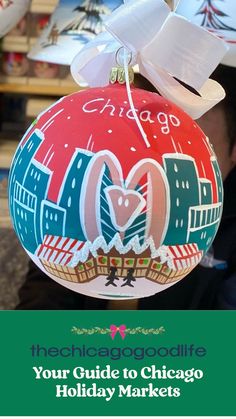 a chicago christmas ornament hanging from a tree with the chicago skyline painted on it