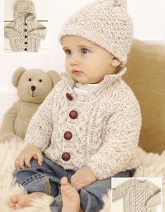 a baby sitting on top of a bed wearing a knitted hat and sweater with buttons