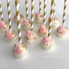 there are many candles that have pink flowers on them and one is white with gold stripes