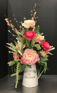 a white vase filled with pink flowers and greenery