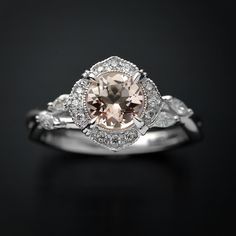 an engagement ring with a pink diamond surrounded by white gold and diamonds on a black background