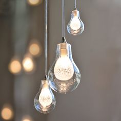 three light bulbs hanging from a ceiling with lights in the background