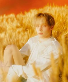 a boy sitting in the middle of a wheat field with his legs crossed and eyes closed