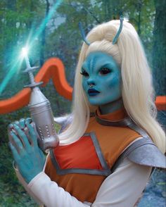 a woman with blue makeup holding a light saber in her hand and wearing an orange outfit