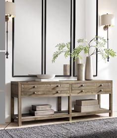 a wooden table with two vases on top of it next to a wall mounted mirror