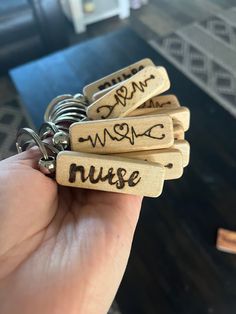 a person holding several wooden keychains with writing on them that read, i am nurse