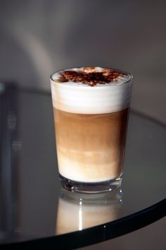 a glass filled with liquid sitting on top of a table next to a cup of coffee