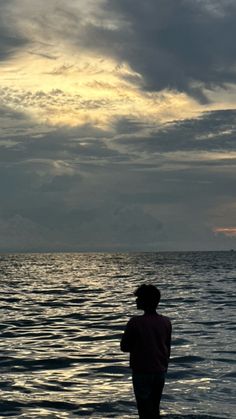 a person standing in the water looking out to sea