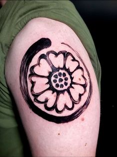 a black and white flower tattoo on the left upper half of a man's arm