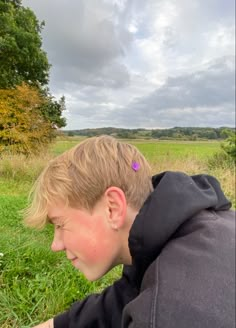 a young boy sitting on top of a lush green field