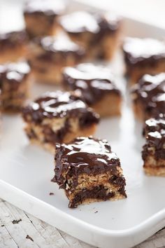 several pieces of dessert sitting on top of a white platter with chocolate frosting