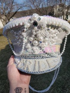 This is an item with iridescent white fabric, pearl strings,  rhinestone embellishments along with an embroidery trim with pearl. This hat is beautiful for any bride! Pearl Strings, Mardi Gras Hats, Rhinestone Outfit, Bridal Hat, Iridescent White, Festival Hat, Rhinestone Embellishments, Costume Hats, Silver Sequin