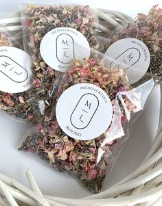 four bags of dried flowers sitting on top of a white wicker basket filled with stickers