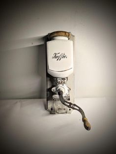 an old fashioned coffee maker is attached to the side of a wall with a pipe