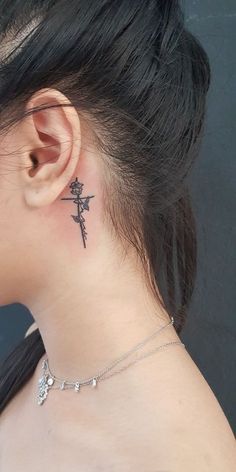 a woman with a small cross tattoo on her left side behind the ear, looking down