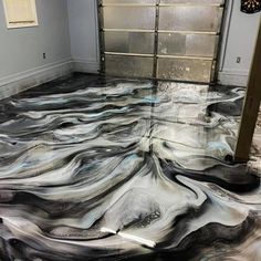 a garage floor that has been painted with black and white swirls on it,