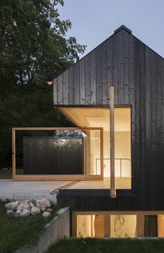 the house is made out of black wood and has glass windows on each side, along with stone steps leading up to it