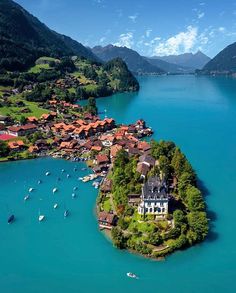 an island in the middle of a lake with boats floating on it's surface