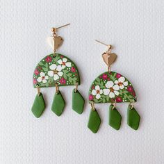 two green and white earrings with flowers on them