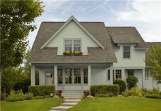 a gray house with steps leading up to the front door and green grass around it