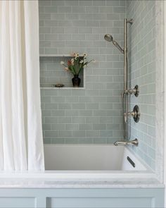 a bath tub sitting under a window next to a shower