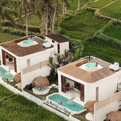 an aerial view of two houses with hot tubs on the roof and grass fields in the background