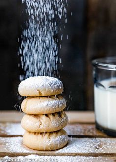 a stack of cookies sitting on top of a wooden table next to a glass of milk