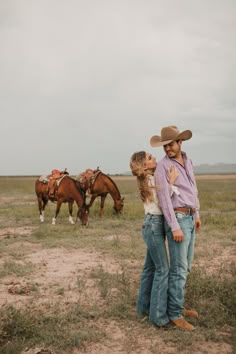 a man and woman standing in front of horses