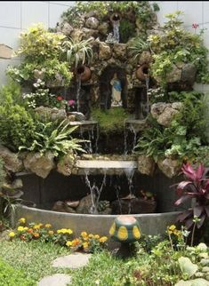 an outdoor fountain surrounded by plants and flowers