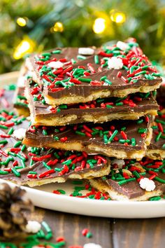 a white plate topped with lots of chocolate and sprinkles next to a christmas tree