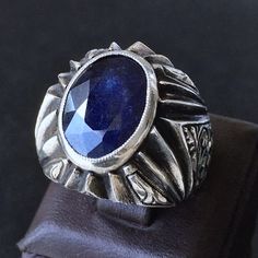 925 STERLING SILVER MENS RING WITH BLUE SAPPHIRE CORUNDUM Completely handcrafted with skill and precision Unique Artisan Jewelry METAL : .925 Sterling Silver GEMSTONE: Blue Sapphire (natural gemstone)  DIMENSIONS OF THE GEMSTONE: 16 x 12 mm  TOTAL WEIGHT: 23.5 gr  SIZE: 9.75 *please ask for resizing Handmade Classic Sapphire Ring In Sterling Silver, Handmade Classic Sterling Silver Sapphire Ring, Silver Round Sapphire Collectible Ring, Silver Sapphire Collectible Ring, Collectible Round Sapphire Ring In Sterling Silver, Collectible Silver Sapphire Ring, Engraved Silver Sapphire Ring, Neelam Ring, Mens Sapphire Ring