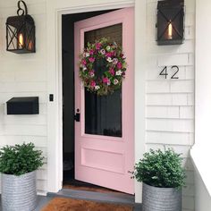 a pink door with two planters on the front porch next to it and number 42