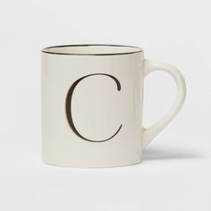 a white coffee mug with the letter c on it's side and black trim