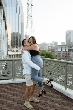 a man and woman hugging each other on a bridge