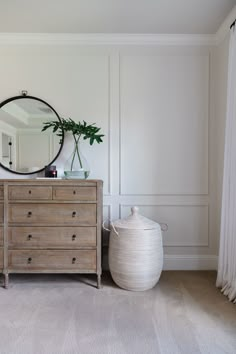 a dresser and mirror in a room with white walls