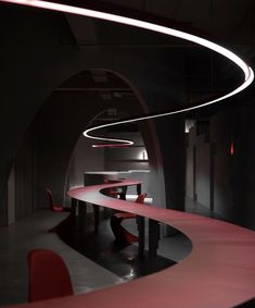 an empty table and chairs in a dark room with red lights on the ceiling above it