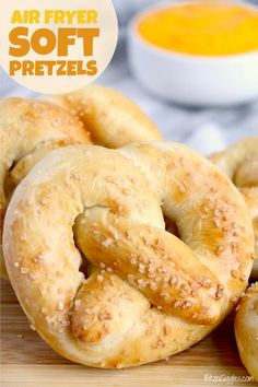 several soft pretzels on a cutting board with an orange dipping sauce in the background