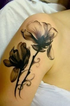 a woman's arm with black and white flowers on the back of her shoulder